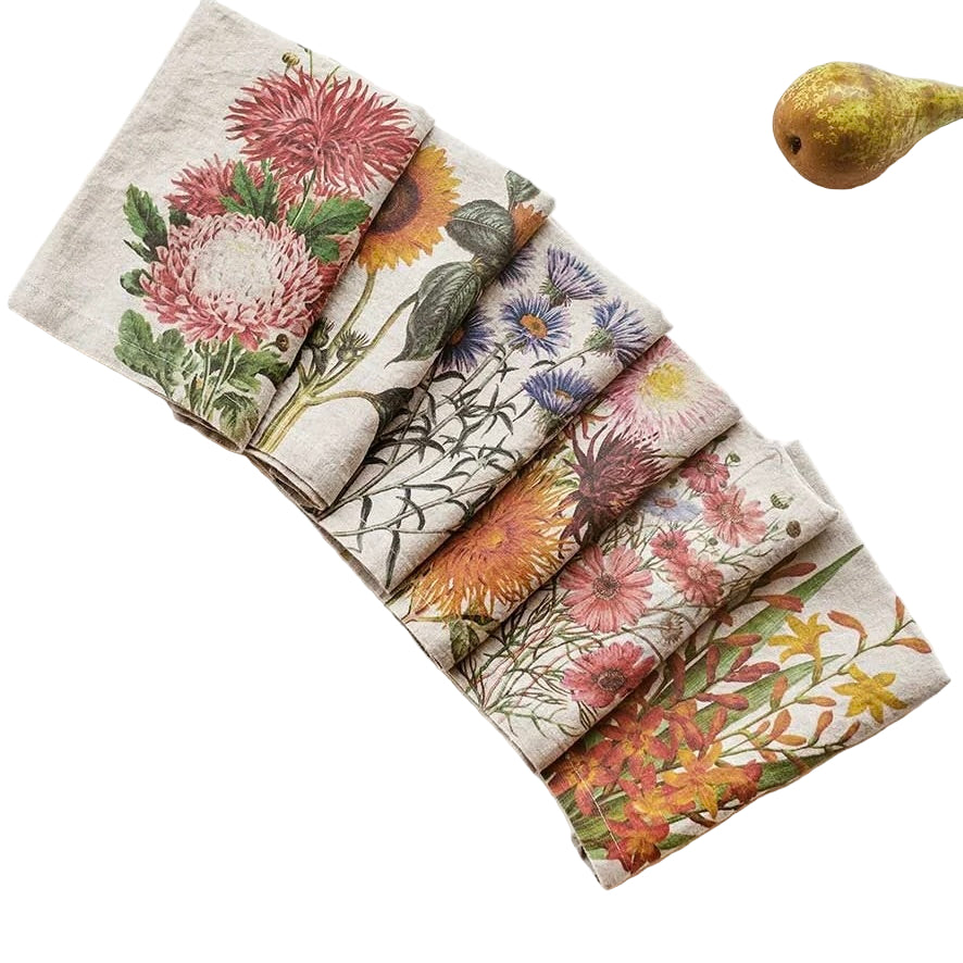 Set of floral-patterned napkins on a white surface with a pear and fork.